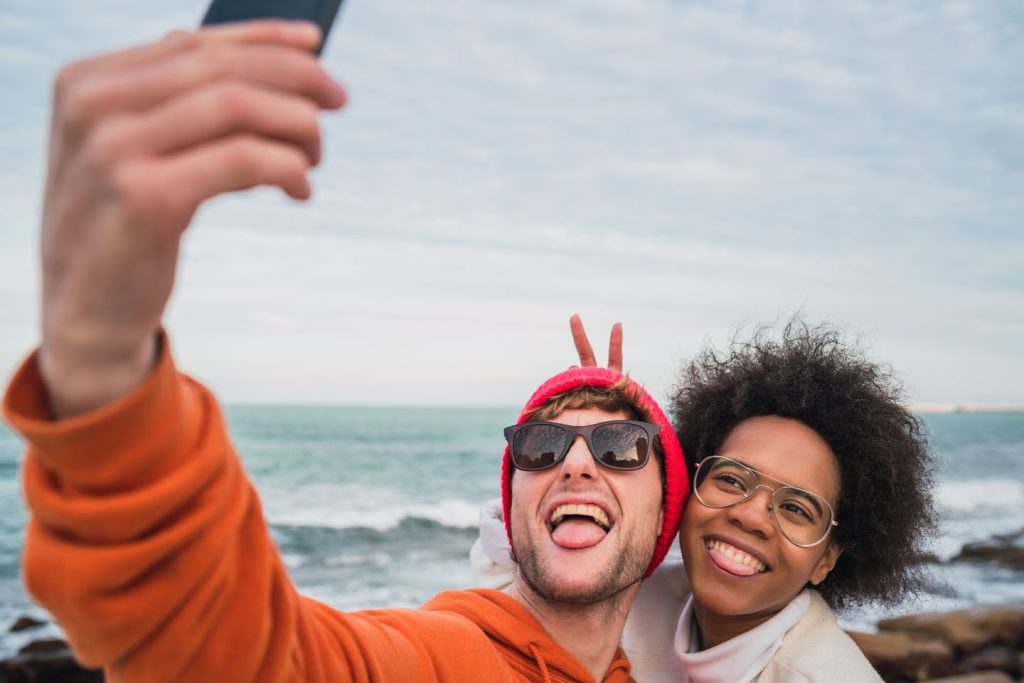 mixed-race couple posing for a selfie with the ocean in the background