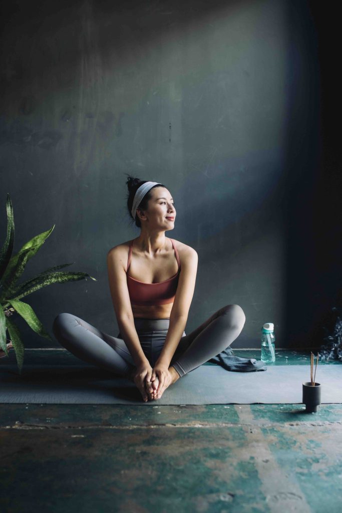 Full-legth shot of a young Asian woman sitting on a yoga mat before exercising.