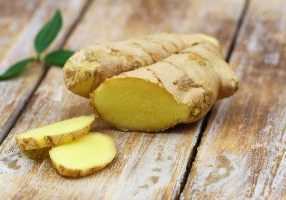 Slices of fresh ginger on rustic wooden surface