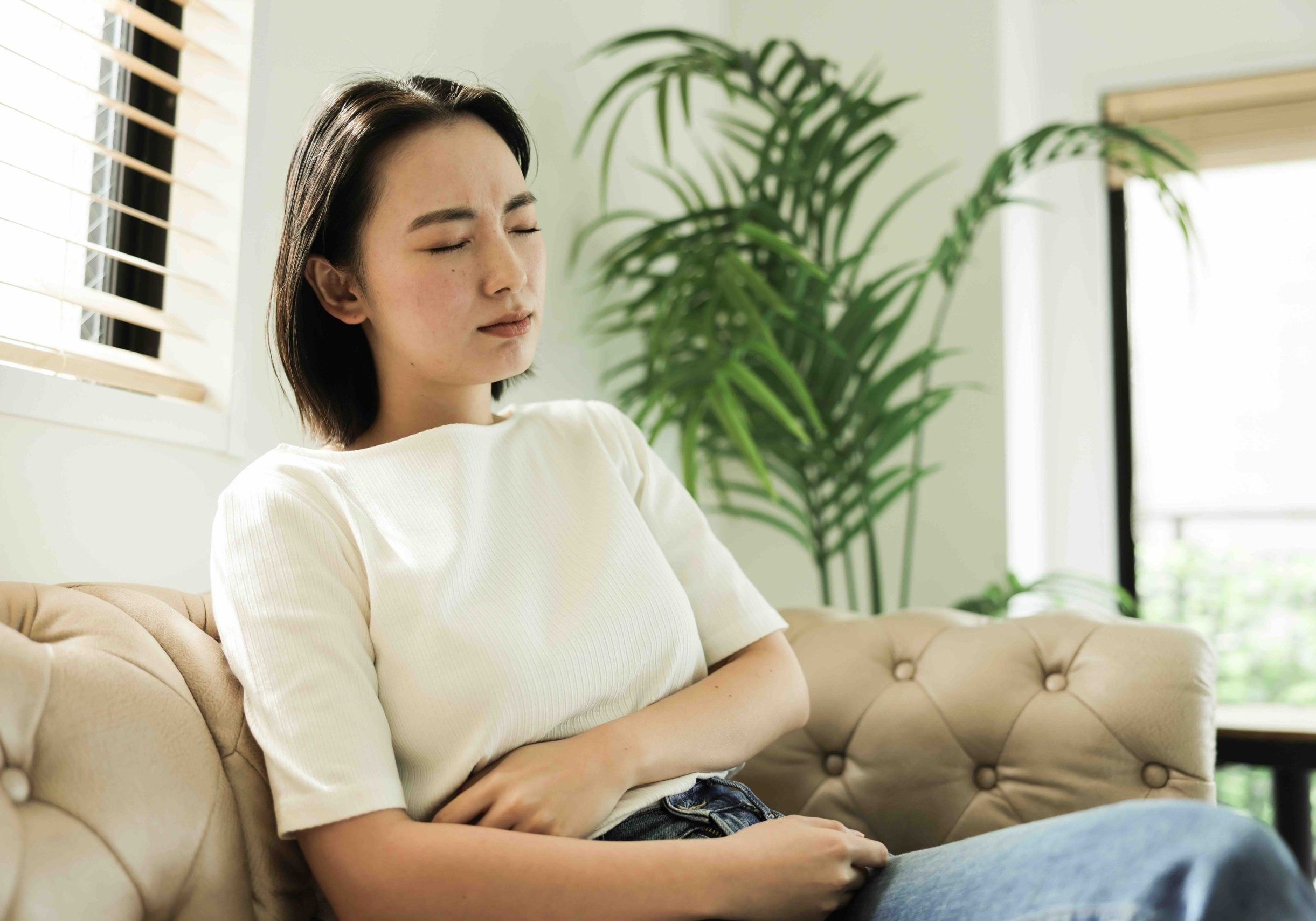 Young Asian woman with stomach ache at home