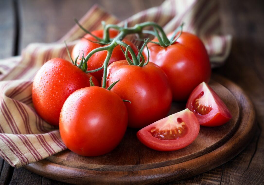 Fresh red ripe tomatoes on the vine on a dark rustic cutting board