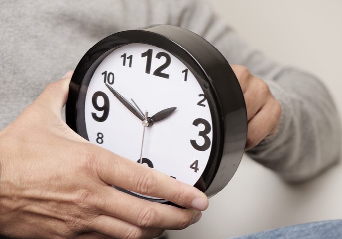 closeup of a young caucasian man adjusting the time of a clock