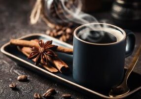 Fresh tasty black espresso cup of hot coffee with cinnamon, anise stars and coffee beans on dark background