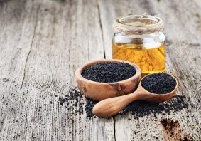 Black cumin oil with seeds on wooden background