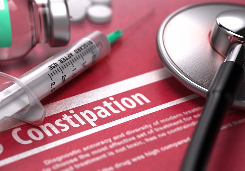 Constipation - Medical Concept on Red Background with Blurred Text and Composition of Pills, Syringe and Stethoscope.