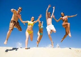 Image of five energetic people jumping at the beach