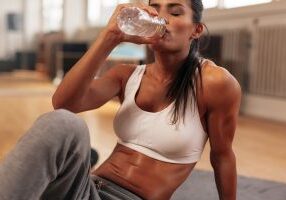 Fitness woman drinking water from bottle. Muscular young female at gym taking a break from workout.
** Note: Shallow depth of field