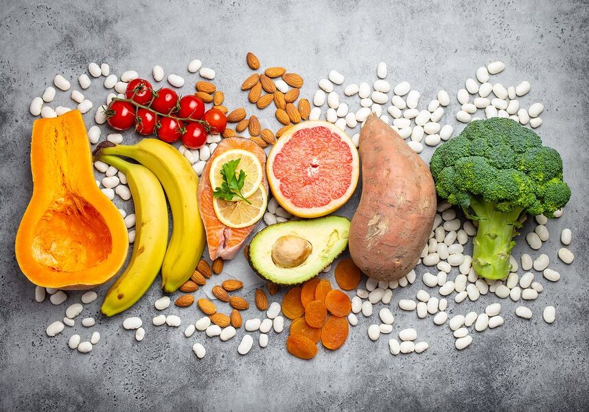 Vegetables, fruit and foods containing potassium over gray stone background, top view. Natural sources of potassium, vitamins and micronutrients for healthy balanced diet and avitaminosis prevention