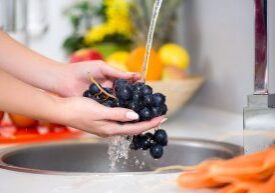 woman's hands washing a fresh grapes under the tap