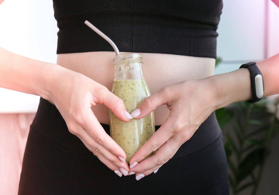 holding smoothie bottle over stomach