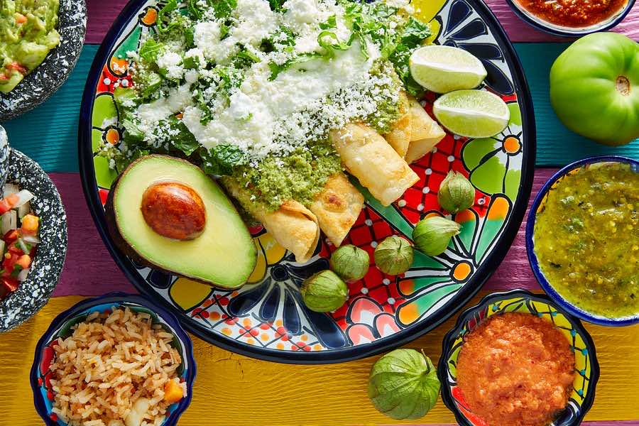 Green enchiladas Mexican food with guacamole and sauces on color ...