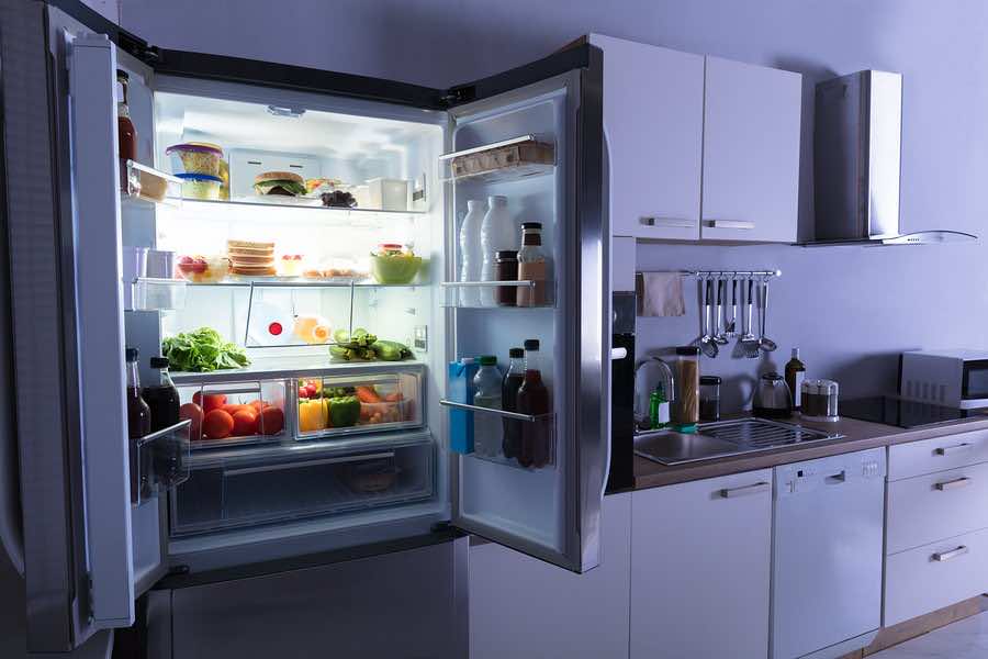 Open Refrigerator Full Of Juice And Fresh Vegetables In Kitchen
